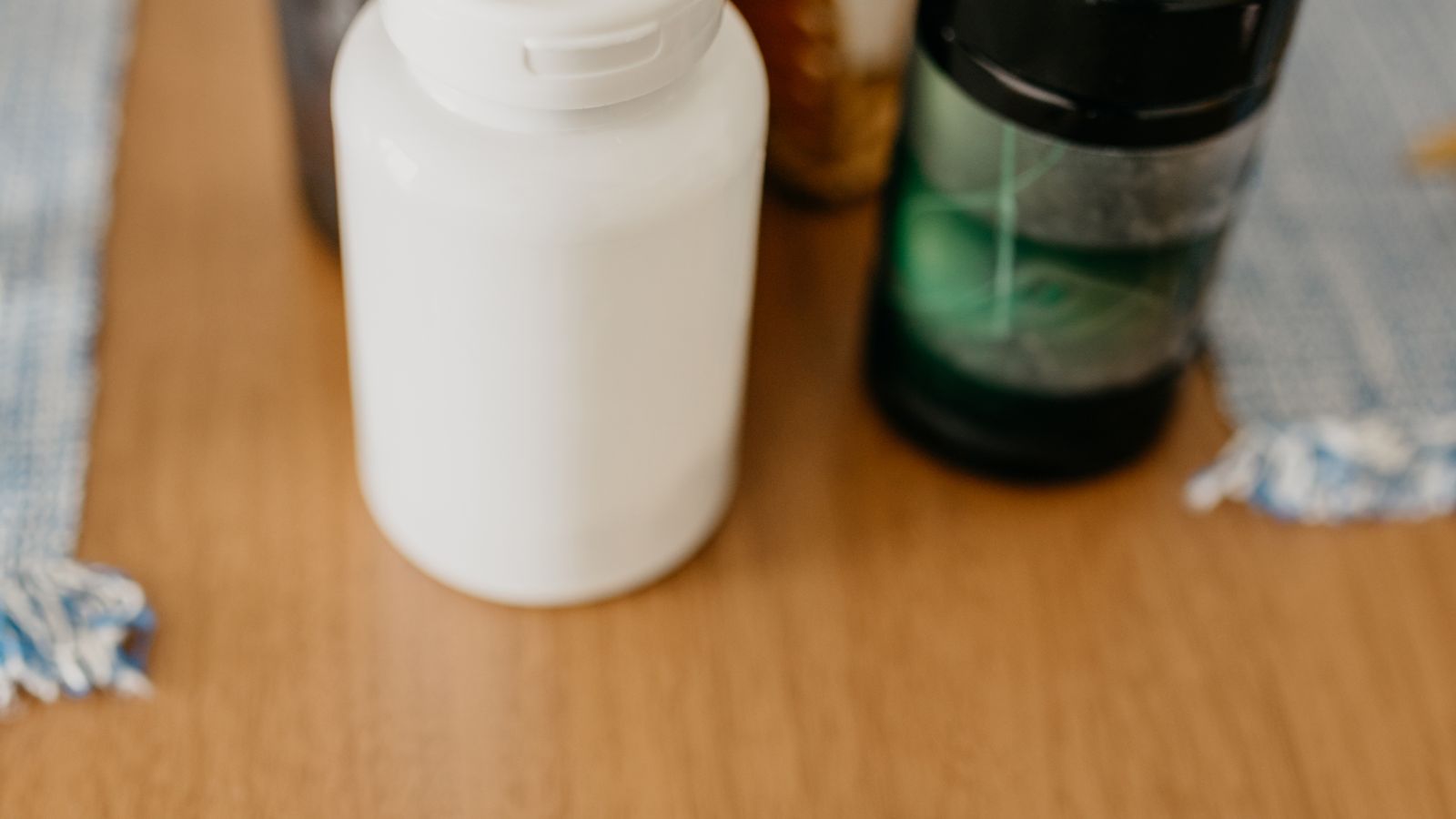 Supplement bottles and capsules on a wooden table, representing the best supplements to lower cortisol.